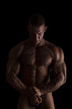 Sexy shirtless bodybuilder isolated on black background. Extreme strength, muscles and fitness.