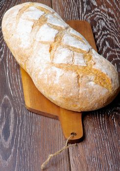 Big Loaf of White Wheat Bread Full Body on Wooden Cutting Board closeup on Hardwood background