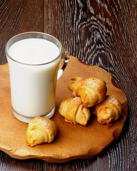 Homemade Croissant Cookies with Jam  and Glass Cup of Milk on Wooden Plate closeup on Rustic Wooden background