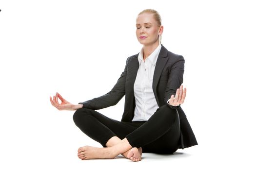 blonde businesswoman sitted on the floor doing a yoga position with her eyes closed