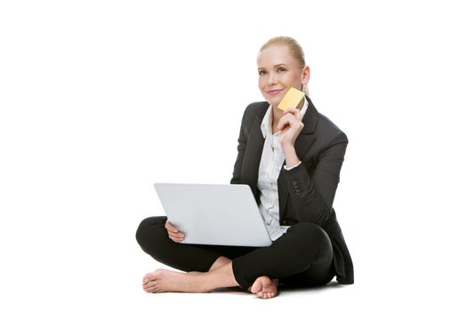 blonde businesswoman seated on the floor holding credit card and buying online