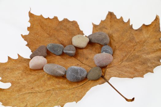 Heart shape made of stone on autumn leaf