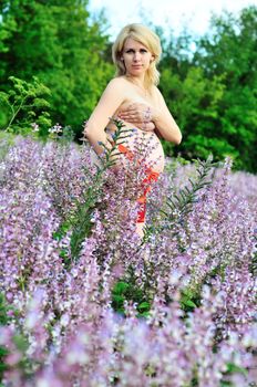 beauty blonde pregnant woman at one with nature with red belt on the belly