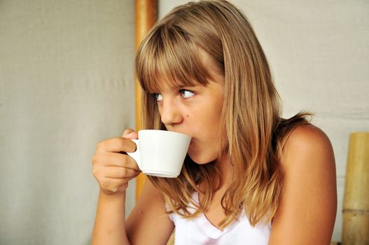 tanned teen girl is drinking something from cup 