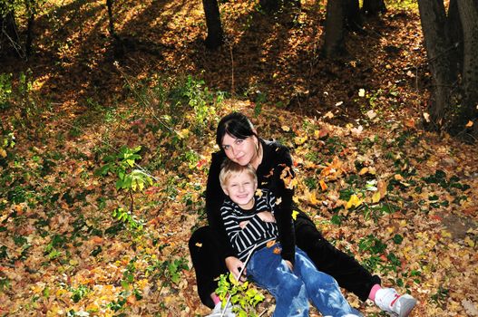 mother and son have a fun in the forest during leaf shedding 