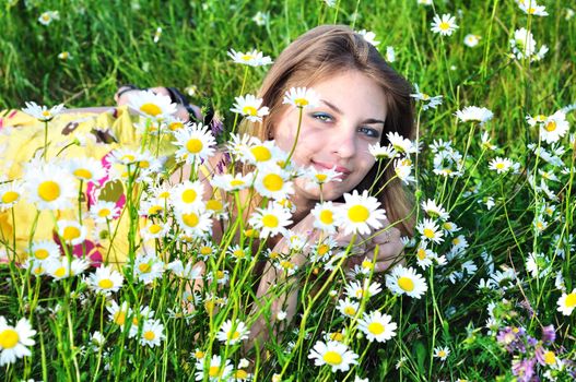 tender girl in daisy flowers on meadow 