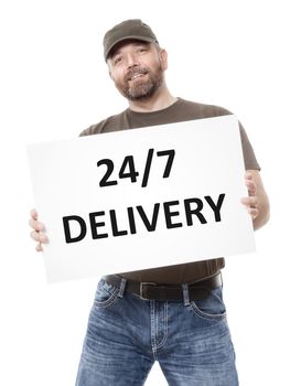 A bearded man holding a white board with the message 24/7 delivery