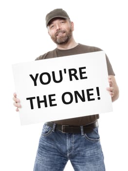 A bearded man holding a white board with the message you're the one!