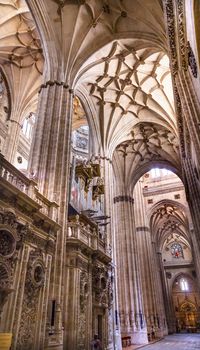 Stone Columns Stained Glass New Salamanca Cathedral Spain.  The New and Old Cathedrals in Salamanca are right next to each other.  New Cathedral was built from 1513 to 1733 and commissioned by Ferdinand V of Castile, Spain.