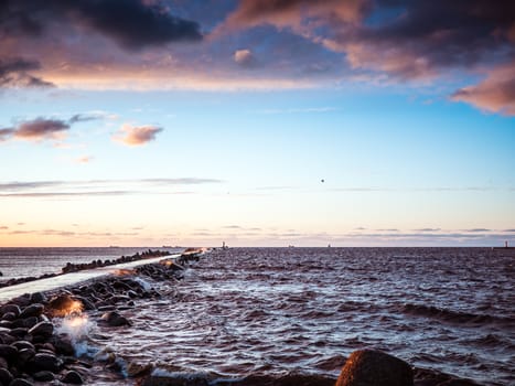 Sunset on the coast of the Riga Gulf at dawn with rocks in foreground