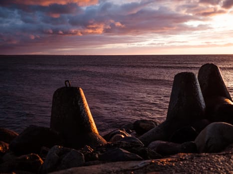 Sunset on the coast of the Riga Gulf at dawn with rocks in foreground