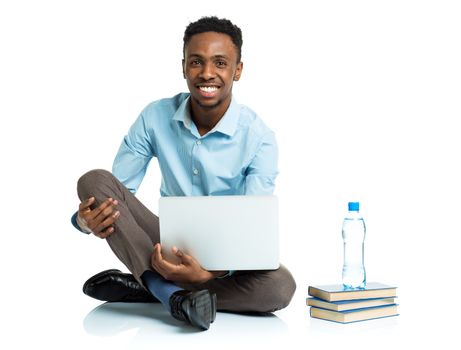 Happy african american college student with laptop, books and bottle of water sitting on white background