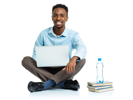 Happy african american college student with laptop, books and bottle of water sitting on white background