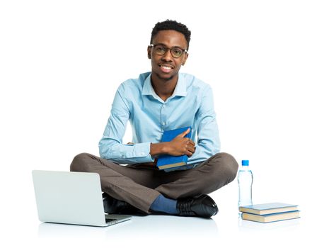 Happy african american college student with laptop, books and bottle of water sitting on white background