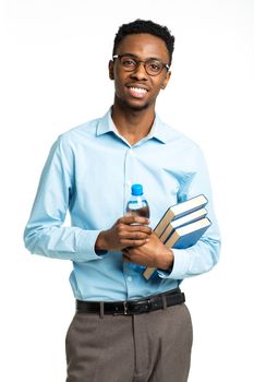 Happy african american college student with books and bottle of water in his hands standing on white background