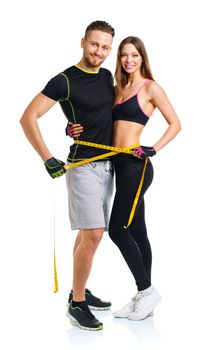 Happy athletic couple - man and woman with measuring tape on the white background