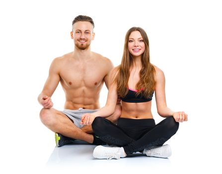 Happy athletic couple - man and woman practicing yoga, doing exercise for relaxation