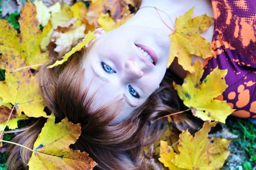 redheaded girl laying in the autumn forest