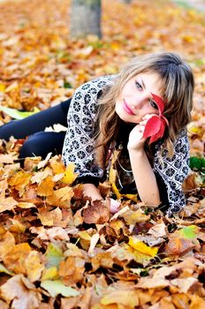 teen girl resting in foliage of autumn park