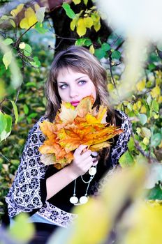 teen girl in forest holding foliage in autumn time