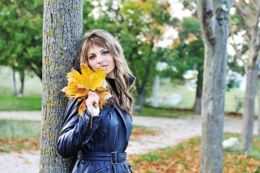 teen girl near autumn tree in the park