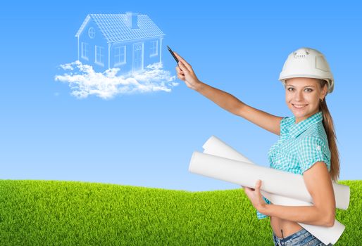 Beautiful girl builder in helmet holding paper scrolls and points to house in clouds. Green field and sky as backdrop
