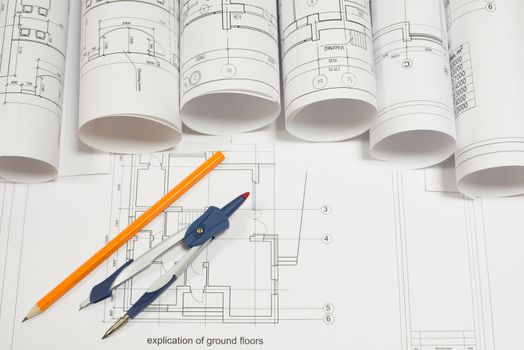 Drawing compasses, pencil and architectural drawings scrolls on explication of ground floor. Concept of building