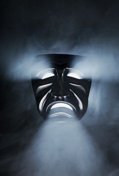 A Black sad mask in smoky back light.