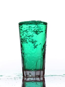 Glass of splashing Turquoise lemonade isolated on white background