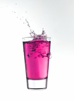 Splash in a glass of pink lemonade isolated on white background