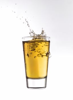 Splash in a glass of orange lemonade isolated on white background