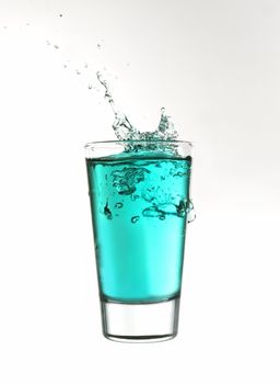 Splash in a glass of turquoise lemonade isolated on white background