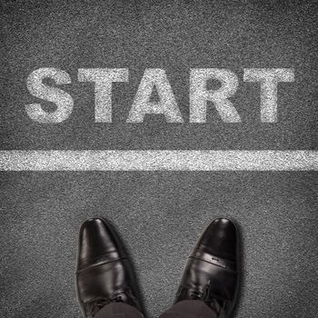 Top view of shoes standing on asphalt road with line and word start. Business concept