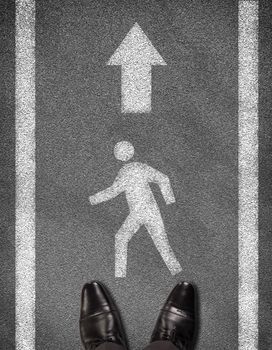 Top view of shoes standing on asphalt road with two line and pedestrian sign. Business concept