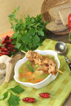 Poultry consomme with chicken skewers on a napkin