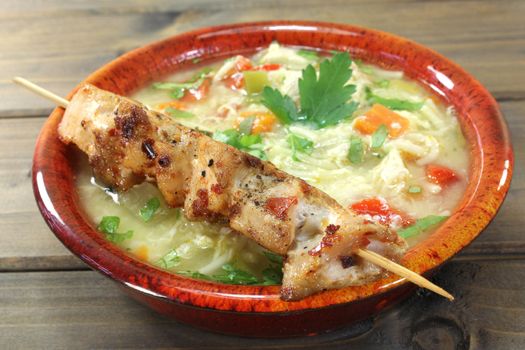Chicken soup with chicken skewers, parsley and noodles