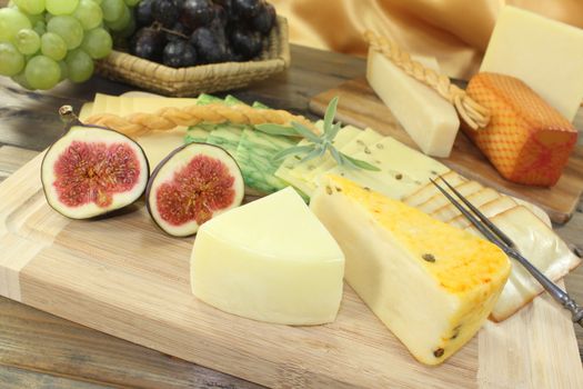 great selection of cheese with fork, grapes and figs