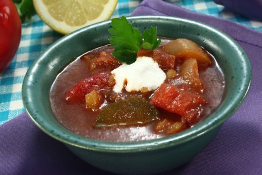 Soljanka in a soup bowl with bread and a dollop of cream