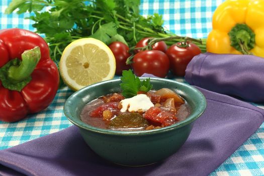 Soljanka in a soup bowl with sausage and a dollop of cream