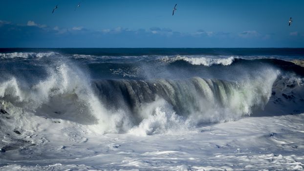 A large wave crashes on the Northern California coastline.