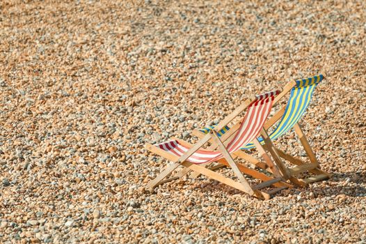 two deckchairs on a pebbled beach in summer