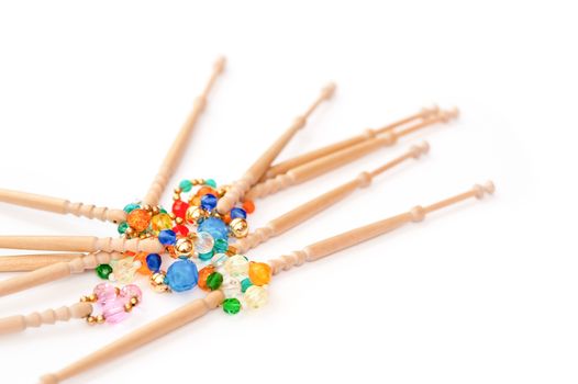 wooden lacemaking bobbins and decorative beads on white