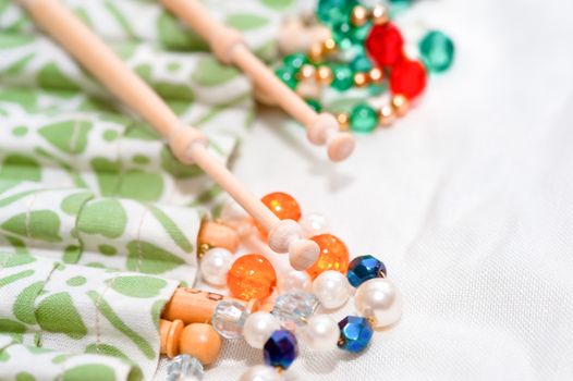 wooden lacemaking bobbins and decorative beads on white linen