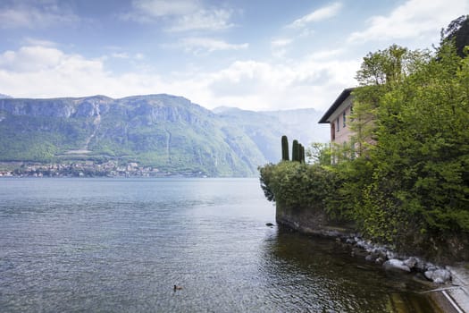 A beautiful house really close to the lake surrounded by green trees and plants in Bellagio, Italy