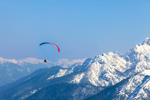 A man having fun with a paraglider over the mountains of Tarvisio, Italy