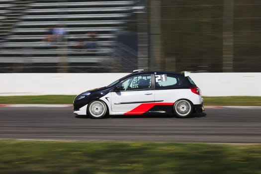 A white small racing car running in the circuit of Monza, Italy