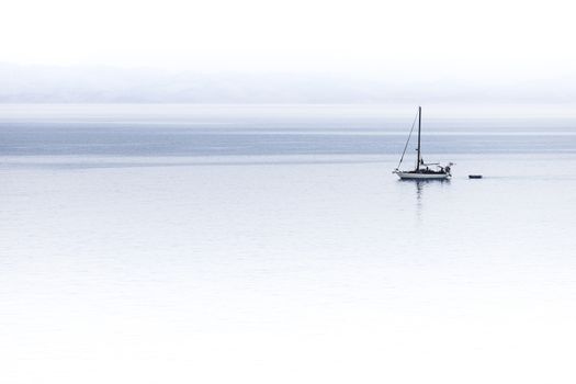 A sailboat navigating with calm and peace alone in the ocean