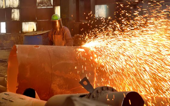worker using torch cutter to cut through metal