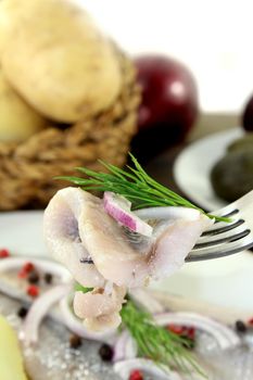 a plate of pickled herring fillet, boiled potatoes, beetroot and pickled gherkins