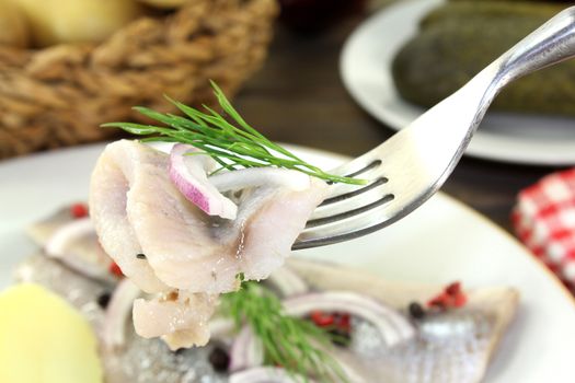 a plate of pickled herring fillet, boiled potatoes, beetroot and pickled gherkins